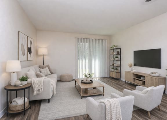 A living room with a white couch, a wooden coffee table, and a flat-screen TV mounted on the wall.