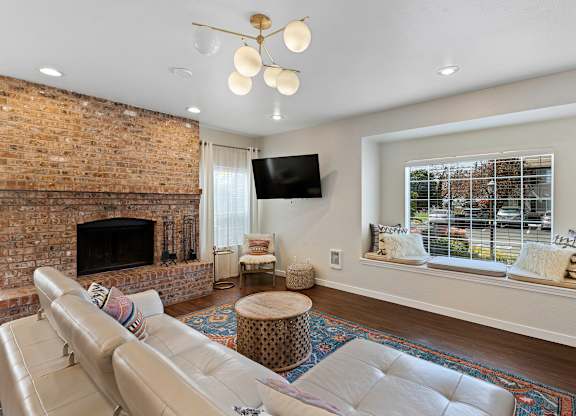 Spacious Living Room with a stone fireplace and river rock mantle with a large window at Serra Vista Apartment Homes, Lynnwood, 98087