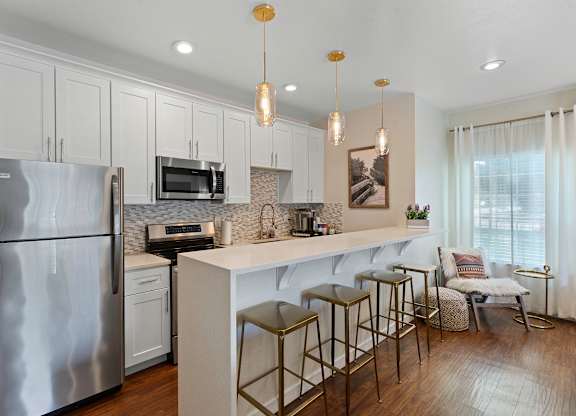 Stunning Kitchen with effieincet appliance, pendant lighting, and bar stool seating at Serra Vista Apartment Homes, Lynnwood, WA
