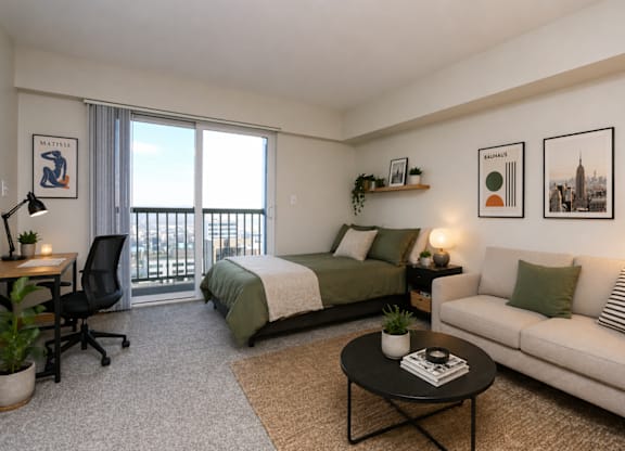 A well-lit bedroom with a balcony overlooking the city.