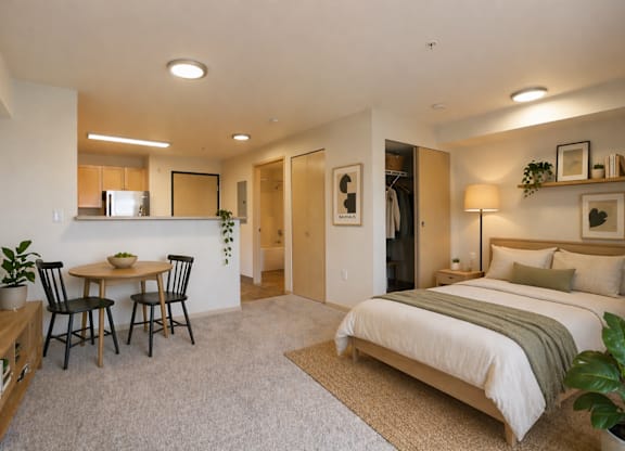 A bedroom with a bed, a table and chairs, and a television.