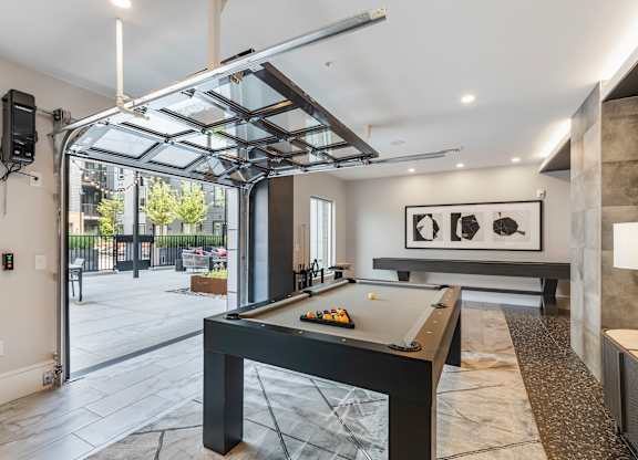 Billiards and game room with garage doors opening to outside patio