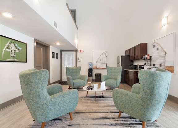 A living room with a green chair and a white wall at Lakes Edge Apartments, North Carolina, 27409