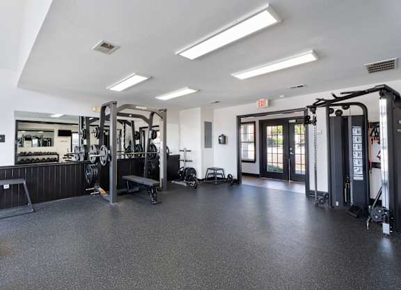 A gym with a variety of equipment including treadmills, weights, and exercise machines. at Village on the Lake Apartments, North Carolina