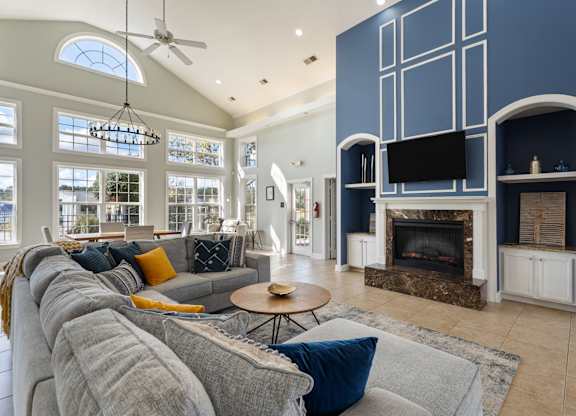 A living room with a grey couch and a fireplace. at Village on the Lake Apartments, Spring Lake, 28390