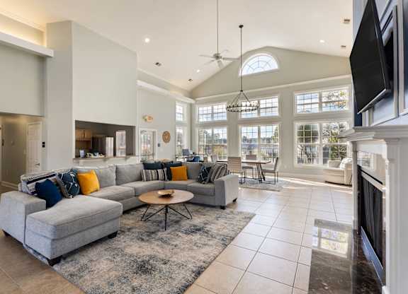 A modern living room with a grey sofa and a black television at Village on the Lake Apartments, Spring Lake