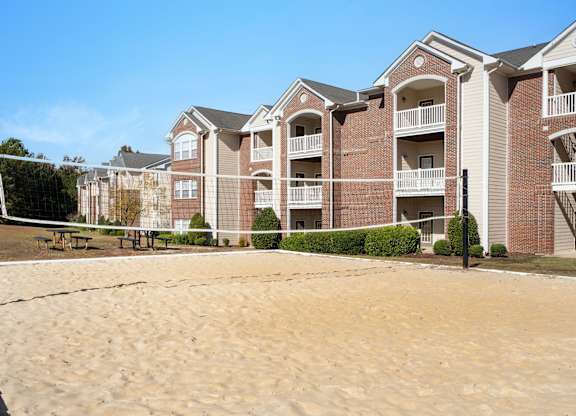 A sand volleyball court in front of apartment buildings. at Village on the Lake Apartments, Spring Lake