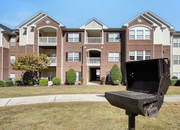 A bench with a laptop on it is in front of a building. at Village on the Lake Apartments, Apartments, Spring Lake, NC