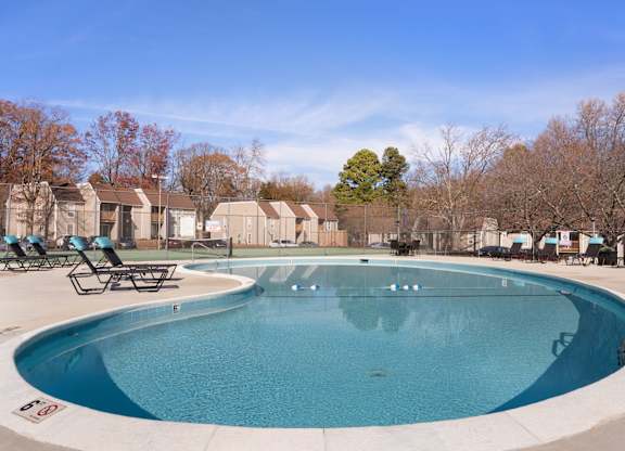 A large outdoor swimming pool surrounded by lounge chairs and trees at Lakes Edge Apartments, Apartments, Greensboro, NC