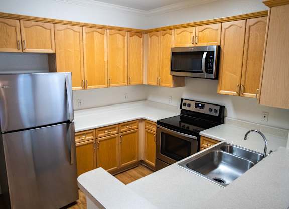 A kitchen with wooden cabinets and a stainless steel refrigerator.