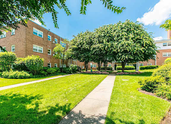 A tree-lined walkway leads to a brick building. at Park Georgetown Apartments, Virginia