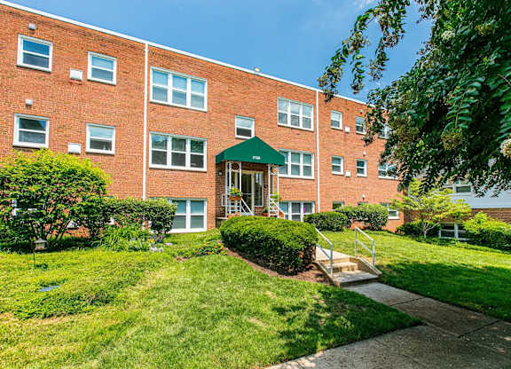 A red brick building with a green roof and a small garden in front. at Park Georgetown Apartments, Virginia, 22209