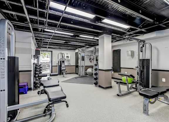 A gym with a variety of equipment including a squat rack, bench, and weights. at Park Georgetown Apartments, Arlington