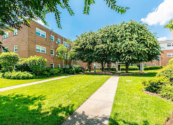 A tree-lined walkway leads to a brick building. at Park Georgetown Apartments, Arlington