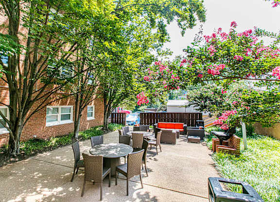 A patio with a table and chairs surrounded by trees. at Park Georgetown Apartments, Virginia, 22209