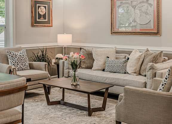 A living room with a grey couch, a coffee table, and a painting on the wall.
