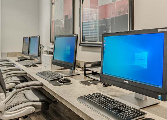 A row of Dell monitors are on a desk.