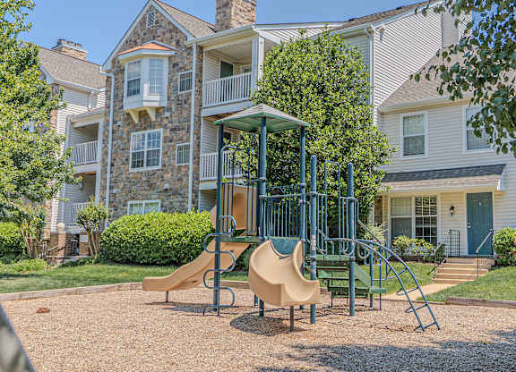 A playground with a slide and a swing set in front of a building.
