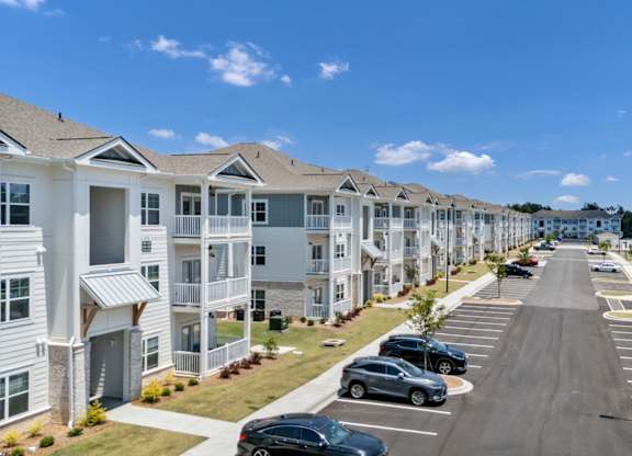 A row of houses with cars parked in front.