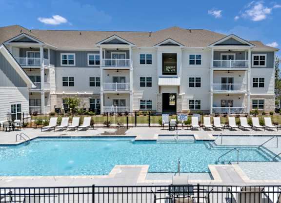 A large apartment complex with a pool in front.
