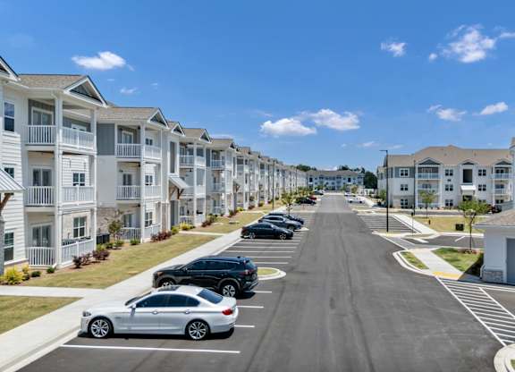 A row of white houses with cars parked in front.