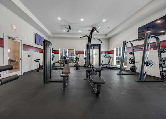 A gym with a variety of equipment including a squat rack, bench, and weights.