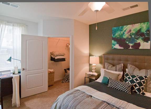A bedroom with a large bed and a painting on the wall. at Kensington Place Apartments, Woodbridge, VA