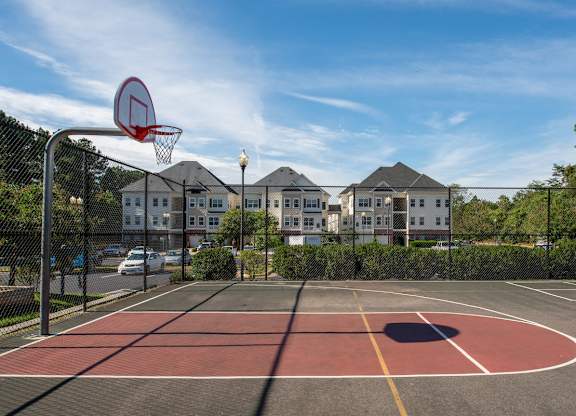 A basketball court with a red and yellow floor and a basketball hoop. at Barrington Park Apartments, Manassas, VA, 20110
