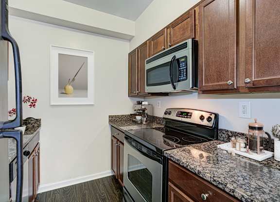 A kitchen with a black microwave above a stove. at Columbia Uptown Apartments, Washington, DC