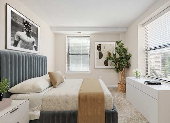 A bedroom with a bed, a dresser, and a window with blinds. at Columbia Uptown Apartments, Washington, DC, 20009