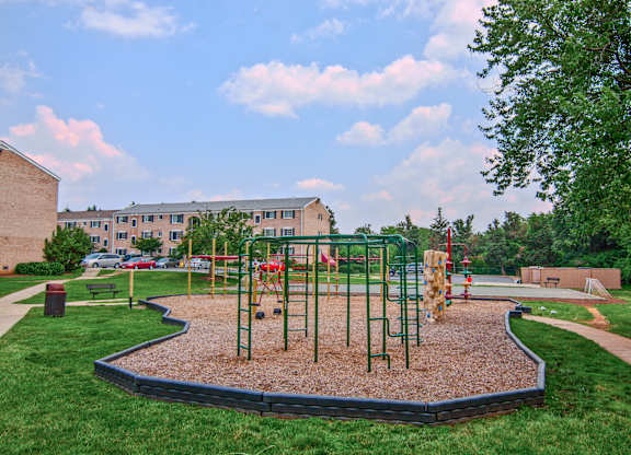 A playground with a red swing set and a green slide at Dulles Glen Apartments, Herndon