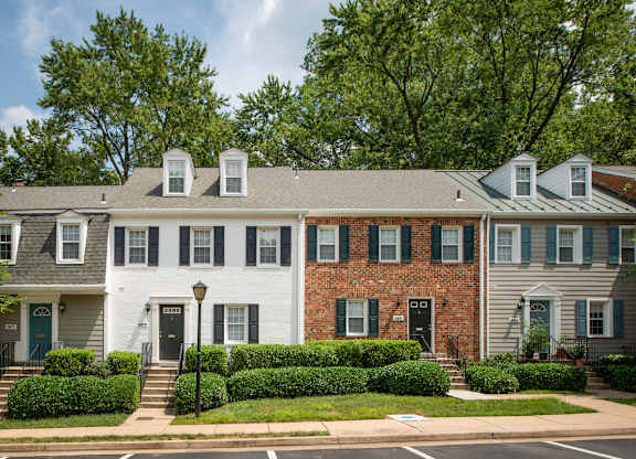 A white house with black shutters and a brick wall at Fairfax Square Apartments, Fairfax