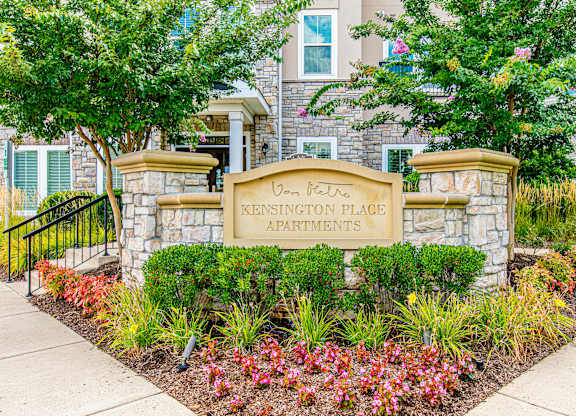 A sign for Kensington Place Apartments is surrounded by flowers and plants. at Kensington Place Apartments, Virginia, 22191