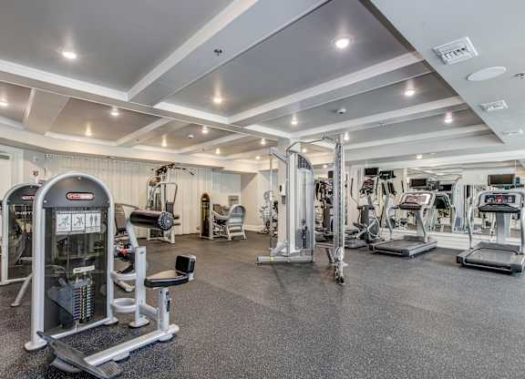 A gym with a variety of equipment including treadmills, weights, and exercise machines. at Kensington Place Apartments, Woodbridge, Virginia