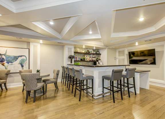 A bar area with a white counter and grey chairs. at Kensington Place Apartments, Woodbridge