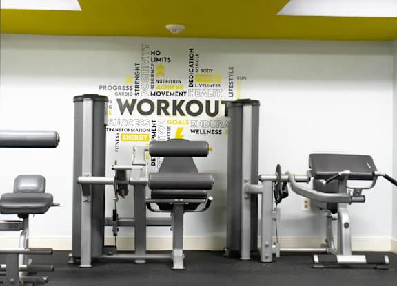 A gym with a row of equipment and a sign that says "workout".