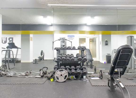 A gym with a variety of equipment including weights and a leg press machine.