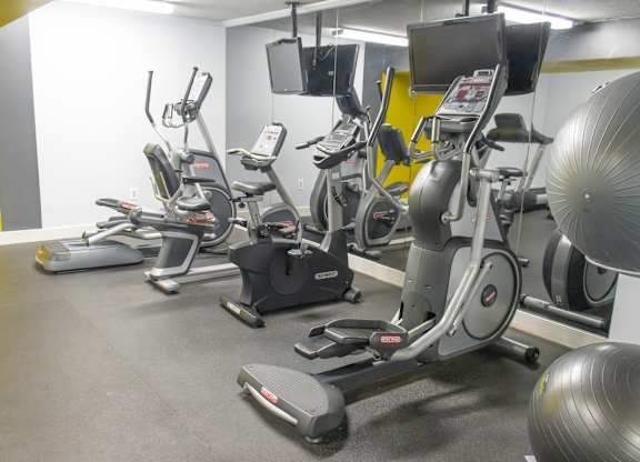 A gym with exercise equipment and a yellow wall.