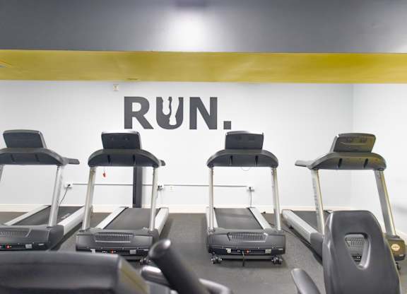 A row of treadmills in a gym with the word RUN on the wall.