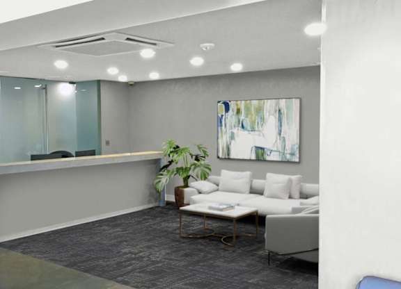 A modern office space with a glass wall, a white couch, and a painting on the wall.