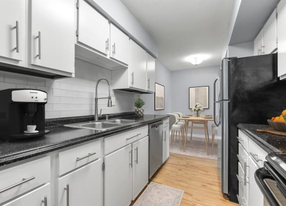 a kitchen with white cabinets and a sink and a refrigerator at West Pointe Apartments in Burlington, NC