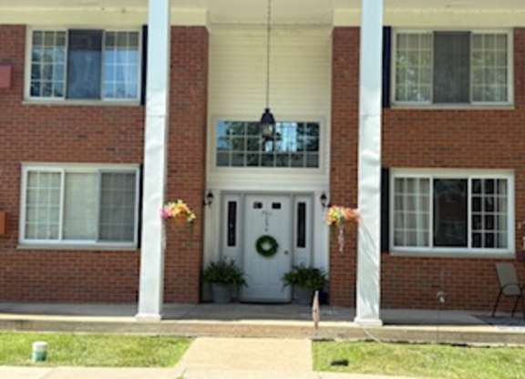A red brick house with a white door and a wreath on the door.