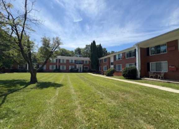A tree stands in the middle of a grassy area in front of a building.