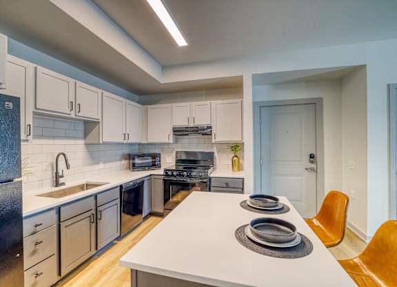 A modern kitchen with a white countertop and a sink.