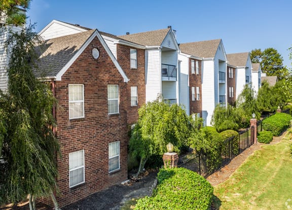 A brick building with a white window is surrounded by greenery at The Trails at Mt. Moriah, Memphis