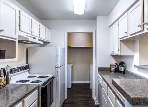 a kitchen with white cabinets and white appliances and granite counter tops at The Trails at Mt. Moriah, Memphis