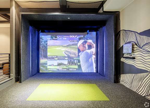 A room with a screen showing a man playing golf.