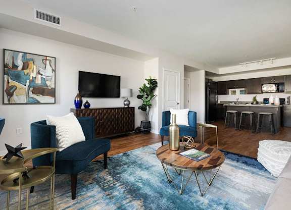 A living room with a blue rug and a brown sofa.