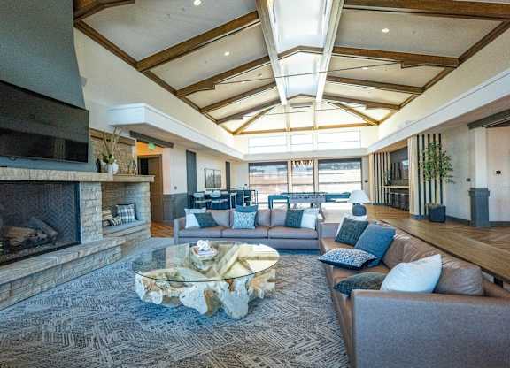 A living room with a stone fireplace and a grey couch.