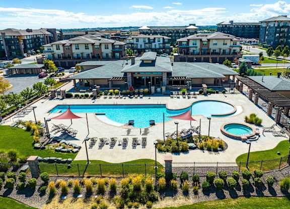 A large outdoor swimming pool surrounded by a fence and a grassy area.